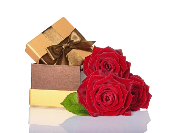 Goldene klassische glänzende Geschenkschachtel mit brauner Satinschleife und Strauß roter Rosen — Stockfoto