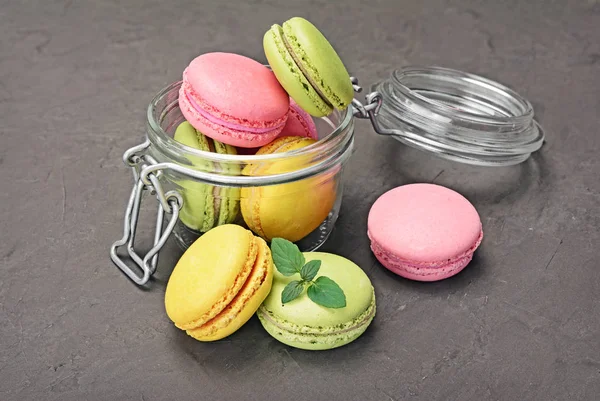 French dessert. Sweet multicolored macaroons or macarons with mint in glass jar