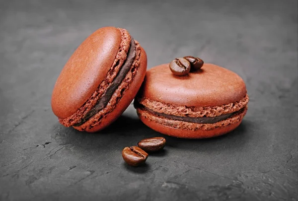 French dessert. Sweet brown chocolate macaroons or macarons with coffee flavor and beans — Stock Photo, Image