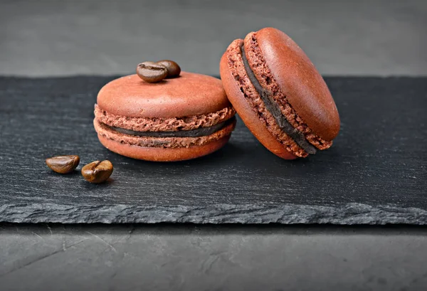 French dessert. Sweet brown chocolate macaroons or macarons with coffee flavor and beans — Stock Photo, Image