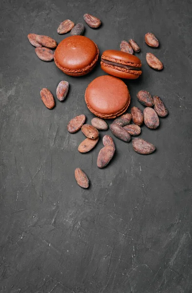 French dessert. Sweet brown chocolate macaroons or macarons with cocoa beans — Stock Photo, Image