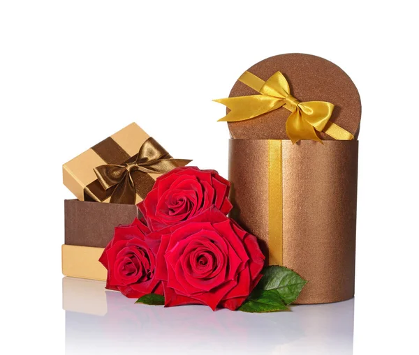 Klassische glänzende Geschenkschachteln mit braunen und goldenen Satinschleifen und einem Strauß Rosen — Stockfoto