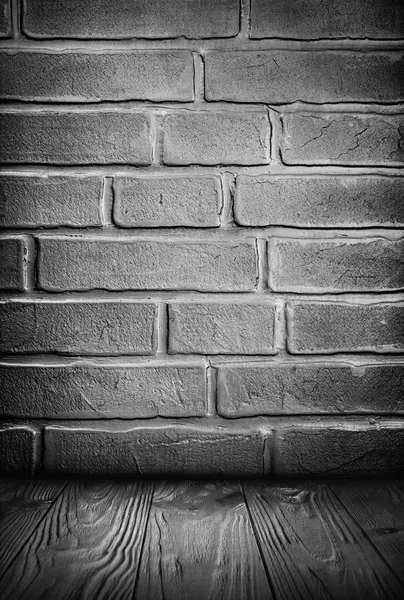 Dark gray grunge textured brick wall and wooden floor