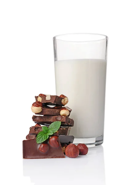 Trozos de chocolate negro con avellanas enteras y un vaso de leche — Foto de Stock