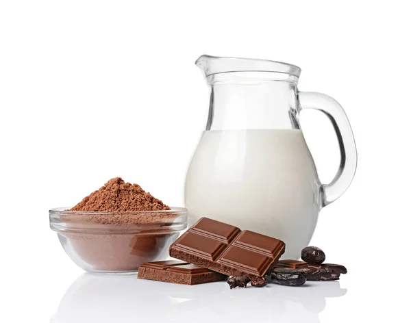 Close-up pieces of chocolate bar with cocoa beans, bowl of cocoa powder and glass jug of milk — Stock Photo, Image