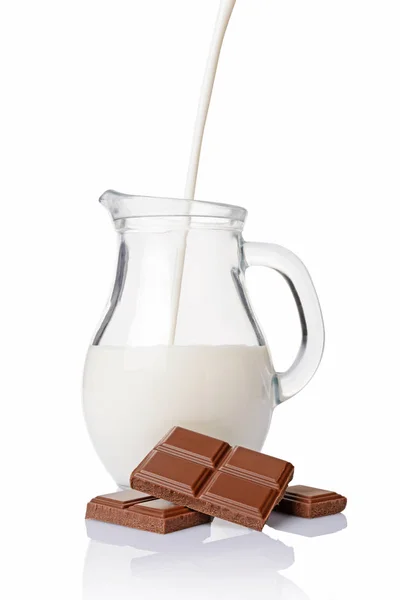 Gros plan morceaux de barre de chocolat avec verser du lait dans une cruche en verre de lait — Photo