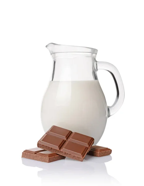 Close-up pieces of chocolate bar with glass jug of milk — Stock Photo, Image