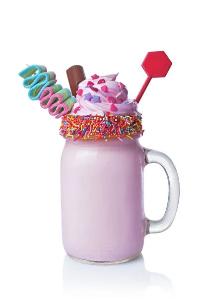 Crazy milk shake with pink whipped cream, chocolate bar and colored candy in glass jar — Stock Photo, Image