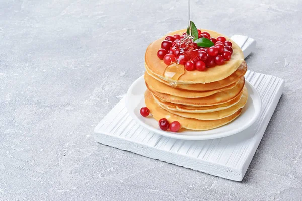Tasty breakfast. Homemade pancakes with fresh cranberry, honey or maple syrup on gray concrete background