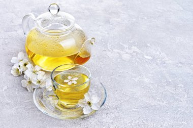 Cam çaydanlık ve yeşil çay ve bahar çiçekleri ile çay fincanı