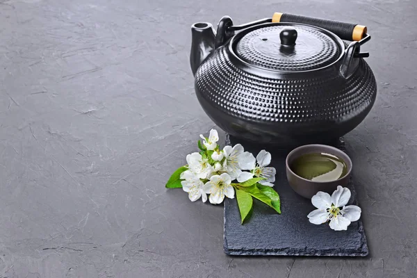 Asian black traditional teapot and teacups with green tea for ceremony