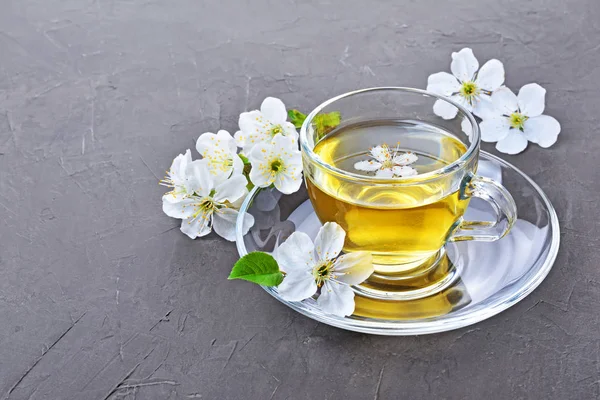 Close-up glass teacup with green tea and spring flowers — Stock Photo, Image