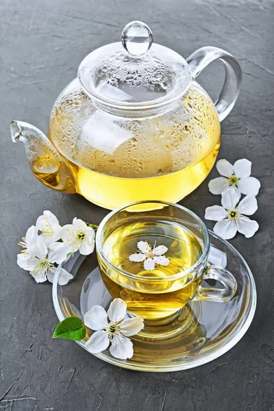 Yakın çekim cam çaydanlık ve yeşil çay ve bahar çiçekleri ile çay fincanı — Stok fotoğraf