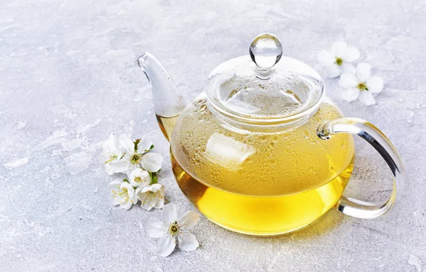 Close-up glass teapot with green tea and spring flowers — Stock Photo, Image