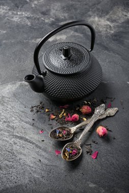 Siyah Japon dökme demir çaydanlık ve gül tomurcuklu çiçek çayı.