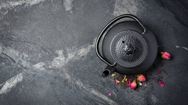 Siyah Japon dökme demir çaydanlık ve gül tomurcuklu çiçek çayı.