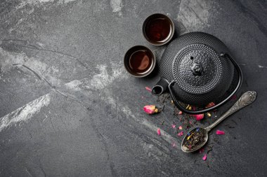 Siyah Japon dökme demir çaydanlık ve gül tomurcuklu çiçek çayı.