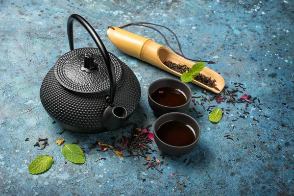 Černá japonská litinová konvice a suchý čaj v bambusovém lopatě s mátou — Stock fotografie