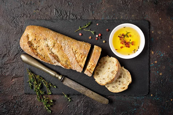 Brödlimpa med kryddig olivolja och gammal rostig bordskniv — Stockfoto