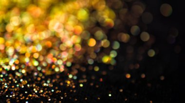 Odaklanmamış altın parıltı ve siyah arkaplan üzerinde bokeh etkisi ile parıltı