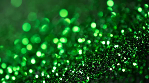 Defocused green glitter and shimmer on abstract bokeh background