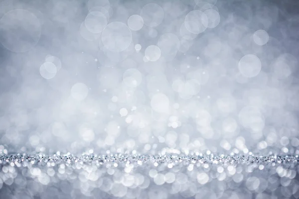 Defocused silver glitter and shimmer on abstract bokeh background