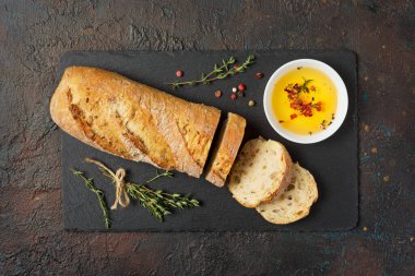 Beyaz kasede zeytinyağlı taze kepekli ekmek ve siyah tahtada kekik baharatı ve siyah grunge backgroun.