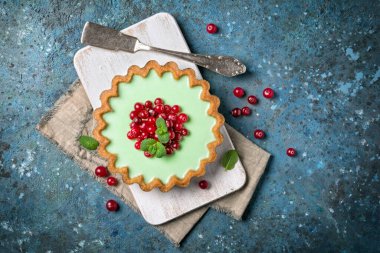 Top view of tasty berry dessert with vintage silver cutlery and fresh green mint on blue concrete background