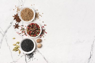 Parlak baharat ve otları küçük kâselerde ve şişelerde karıştırmak beyaz mermer arka planda sağlıklı yiyecekler ve fotokopi alanı içerir.