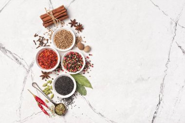 Parlak baharat ve bitkilerin beyaz mermer arka planda ve fotokopi alanındaki sağlıklı yiyecekler için malzeme olarak küçük kâselerde karıştırılmasının üst görüntüsü