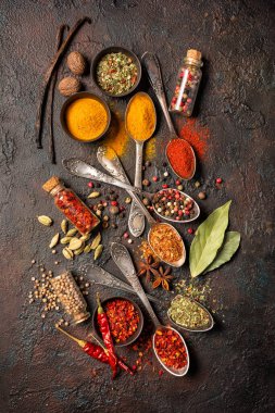 Eskimiş gümüş kaşıklardaki, kaselerdeki ve şişelerdeki parlak baharatların karışımı kahverengi grunge arka planda sağlıklı yiyecekler için malzeme niteliğindedir.