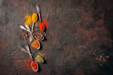 Eskimiş gümüş kaşıklardaki parlak baharatların kahverengi grunge arka planında ve fotokopi alanındaki sağlıklı yiyecekler için malzeme olarak üst görünümü