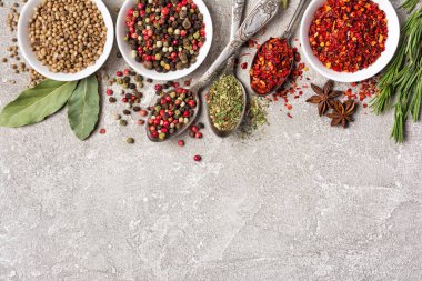 Kaliteli gümüş kaşıklar ve kâselerdeki parlak baharatları gri beton arka planda ve fotokopi alanındaki sağlıklı yiyecekler için malzeme olarak kullanmanın en iyi yolu.