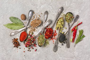 Kaliteli gümüş kaşıklardaki parlak baharatları gri beton arka planda sağlıklı yiyecekler için malzeme olarak kullanmanın en iyi yolu.