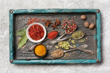 Kaliteli ahşap turkuaz tepsi ve gri beton arka planda sağlıklı yiyecekler için malzeme olarak parlak baharatların üst görüntüsü