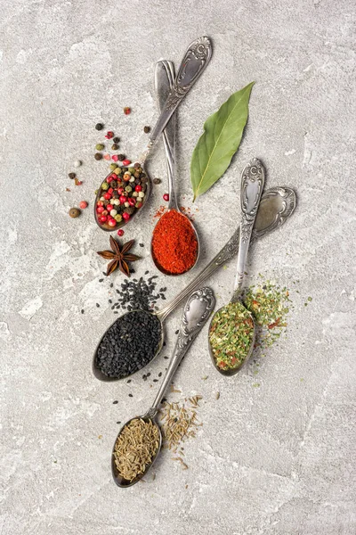 Kaliteli gümüş kaşıklardaki parlak baharatları gri beton arka planda sağlıklı yiyecekler için malzeme olarak kullanmanın en iyi yolu.