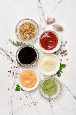 Mayonez, kırmızı ketçap, sarı hardal, yeşil wasabi ve beyaz mermer zemin üzerinde kara soya soslu kâselerin üst görüntüsü.