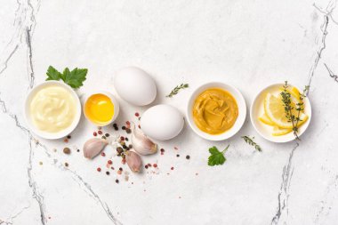 Ev yapımı mayonez malzemelerinin beyaz mermer arka planda hardal, yumurta, baharat olarak üst görünümü