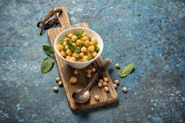 Nane yaprağı aromalı nohutlar vejetaryen yemek malzemesi olarak mavi beton arka planda mavi kaşık ve fotokopi alanı olan