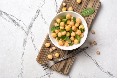 Nane yaprağı aromalı nohut, beyaz mermer arka planda antika çatallı vejetaryen yemeği malzemesi.