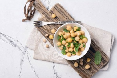 Nane yaprağı aromalı nohut, beyaz mermer arka planda antika çatallı vejetaryen yemeği malzemesi.