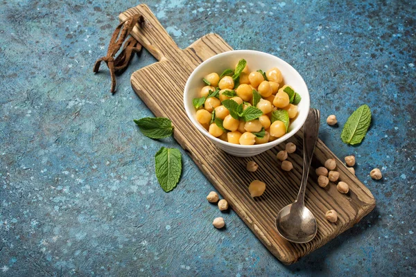 ミントのスパイスとボウルにひよこ豆は コピースペースと青の具体的な背景にヴィンテージスプーンで菜食主義者の食事のための成分として葉 — ストック写真