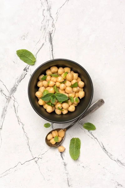 白い大理石の背景に菜食料理の材料としてミントの葉のスパイスとボウルにひよこ豆のトップビュー — ストック写真