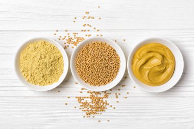 Beyaz kâselerdeki hardal manzarası geleneksel ev yapımı sos ve beyaz ahşap arka planda baharatlı yemek için.