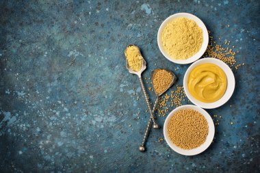 Geleneksel ev yapımı sos için beyaz kâselerdeki hardal manzarası ve mavi beton arka planda kopyalanmış kaliteli kaşıklarla baharatlı yemekler.