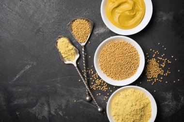 Geleneksel ev yapımı sos ve siyah mermer arka planda siyah kaşık ve fotokopi alanı olan baharatlı yemekler için beyaz kâselere yerleştirilmiş hardal manzarası.