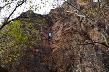 Genç adam dikey tepeye tırmanıyor.