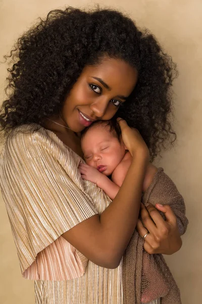 Улыбающаяся мать в золотом платье с новорожденным ребенком — стоковое фото
