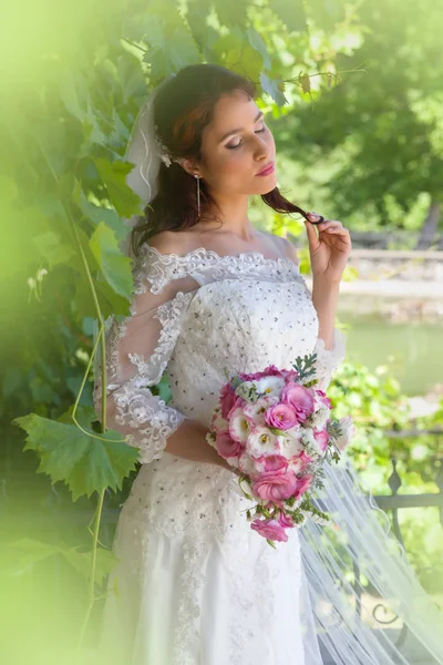 Bride posing in green foliage — Stock Photo, Image