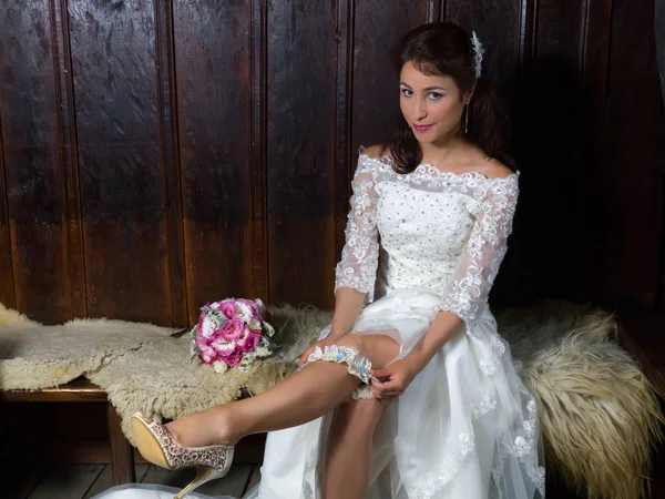 Sexy bride putting on a garter — Stock Photo, Image